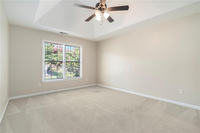 unfurnished room featuring light colored carpet, ceiling fan, and a raised ceiling