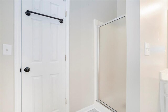 bathroom featuring a shower with door and vanity