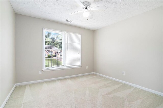 empty room with a textured ceiling, light colored carpet, and ceiling fan