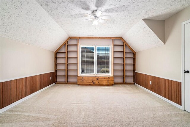 bonus room featuring lofted ceiling, ceiling fan, light carpet, and a textured ceiling