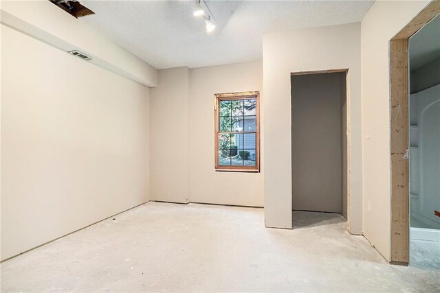 empty room featuring a textured ceiling and rail lighting