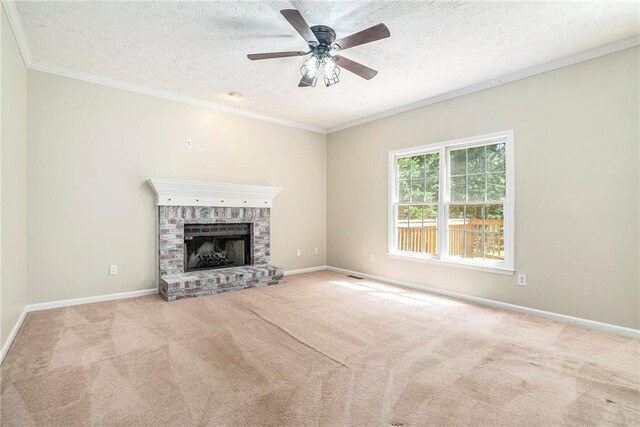 unfurnished living room featuring a fireplace, light colored carpet, ceiling fan, ornamental molding, and a textured ceiling