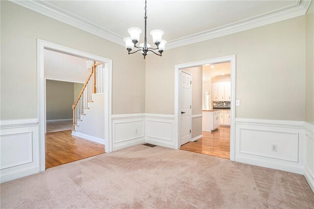 spare room featuring a chandelier, light hardwood / wood-style floors, and ornamental molding