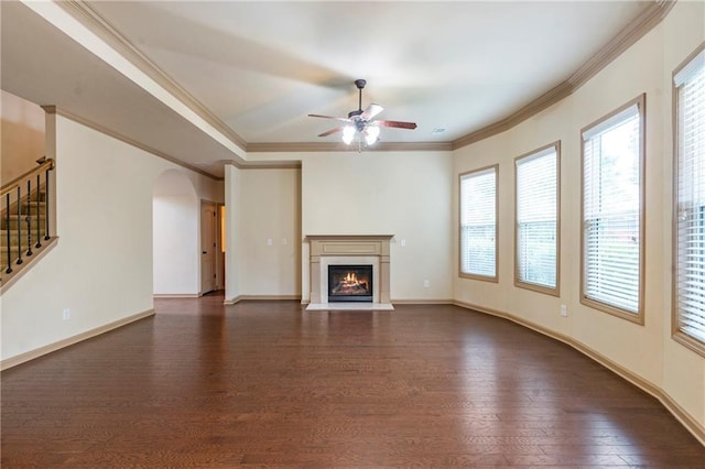 unfurnished living room with a healthy amount of sunlight, arched walkways, ceiling fan, and dark wood-style floors
