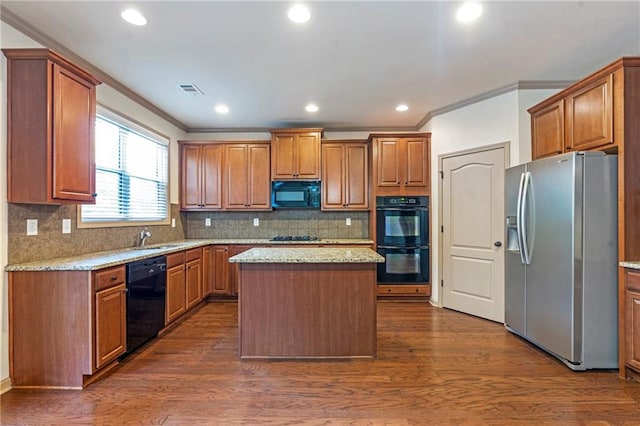 kitchen featuring ornamental molding, a kitchen island, black appliances, and brown cabinets