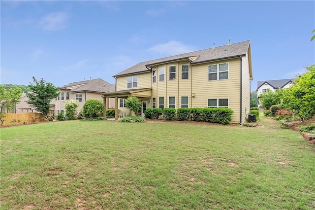 rear view of property featuring a yard and cooling unit