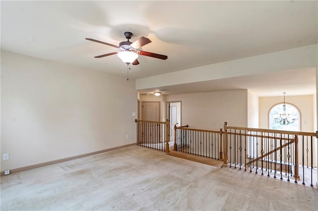 carpeted spare room with baseboards and ceiling fan with notable chandelier