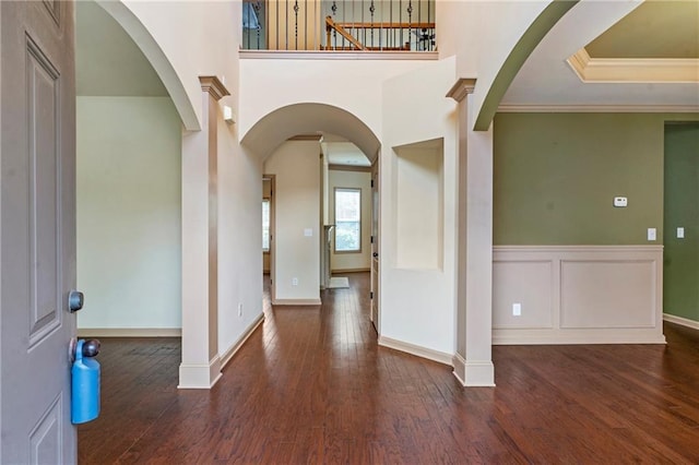 entryway with wood-type flooring, arched walkways, baseboards, and ornamental molding