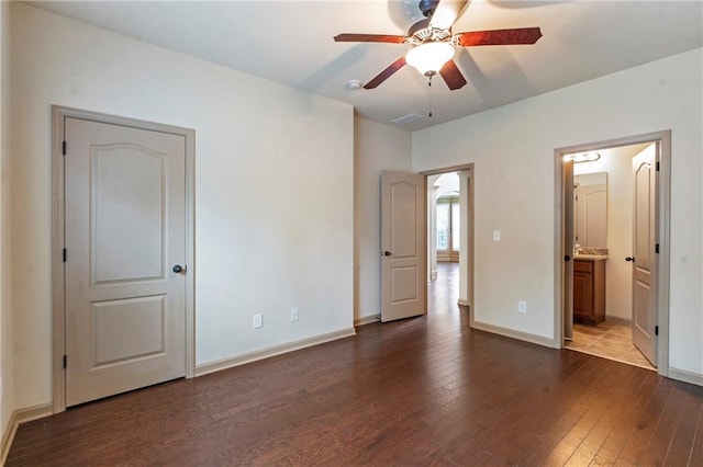 unfurnished bedroom featuring baseboards, ensuite bathroom, hardwood / wood-style floors, and visible vents