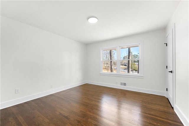 spare room featuring dark wood-type flooring, baseboards, and visible vents