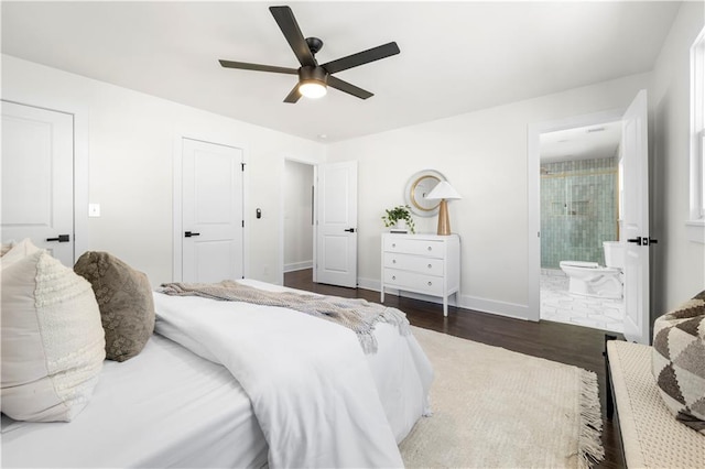 bedroom featuring dark wood-style flooring, ensuite bath, baseboards, and ceiling fan