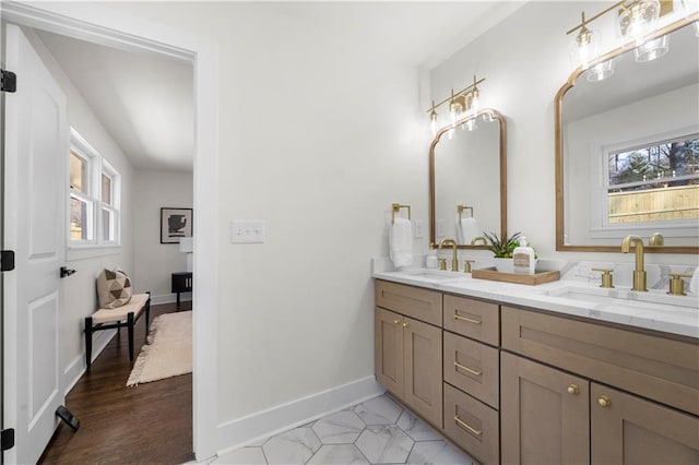 bathroom featuring baseboards, double vanity, and a sink