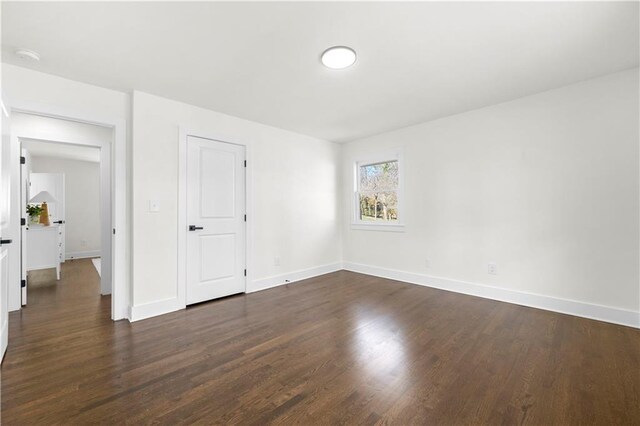 empty room featuring dark wood-style floors and baseboards