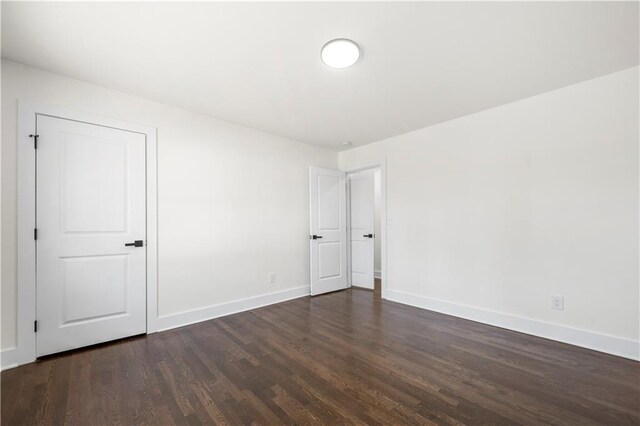 unfurnished room featuring baseboards and dark wood-style flooring