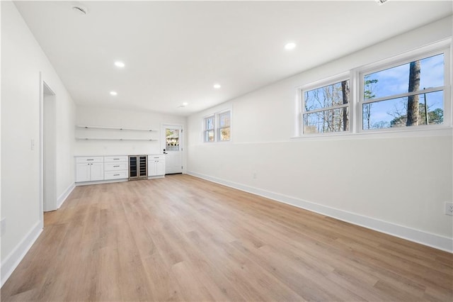 unfurnished living room with light wood-style floors, a dry bar, baseboards, and recessed lighting