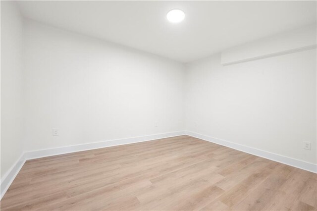 spare room with baseboards and light wood-style floors