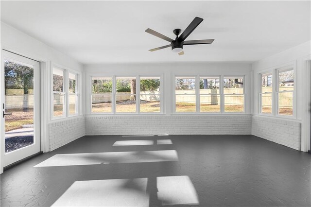 unfurnished sunroom featuring brick wall and concrete flooring