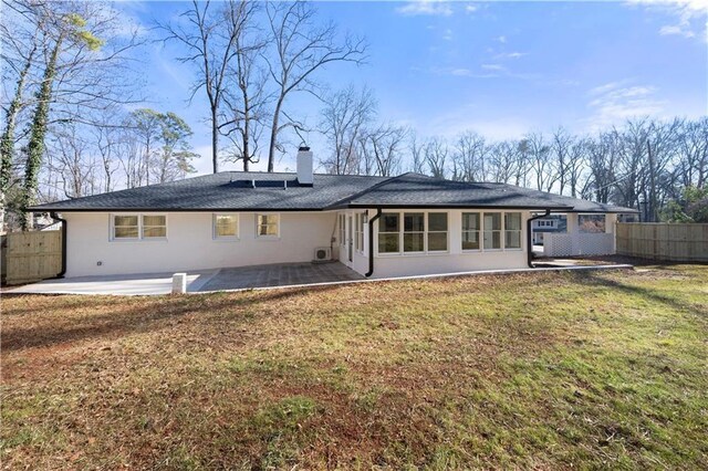 rear view of property with fence, a chimney, a patio area, and a lawn