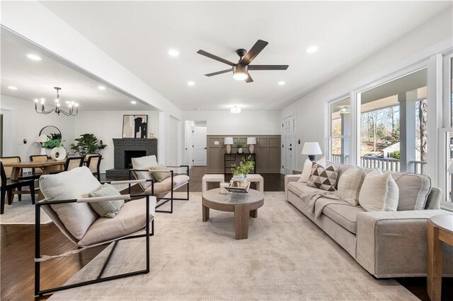 living area featuring light wood finished floors, ceiling fan with notable chandelier, and recessed lighting