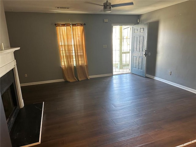 unfurnished living room featuring baseboards, a ceiling fan, dark wood-style floors, and a fireplace