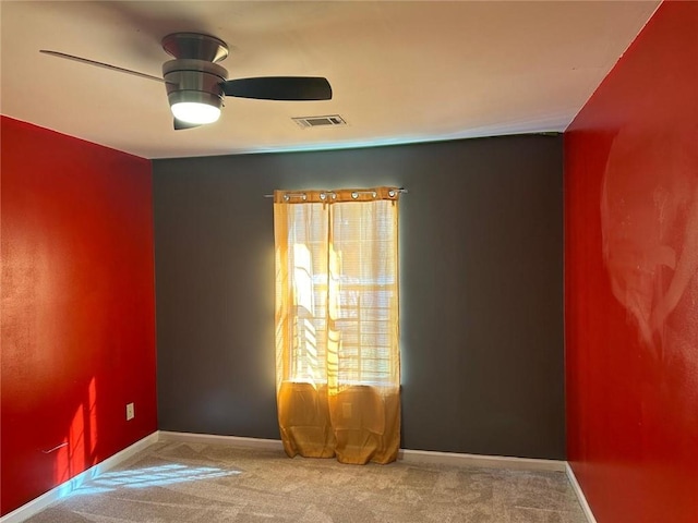 carpeted empty room with a ceiling fan, visible vents, and baseboards