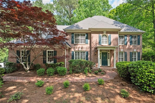 colonial inspired home featuring brick siding and roof with shingles