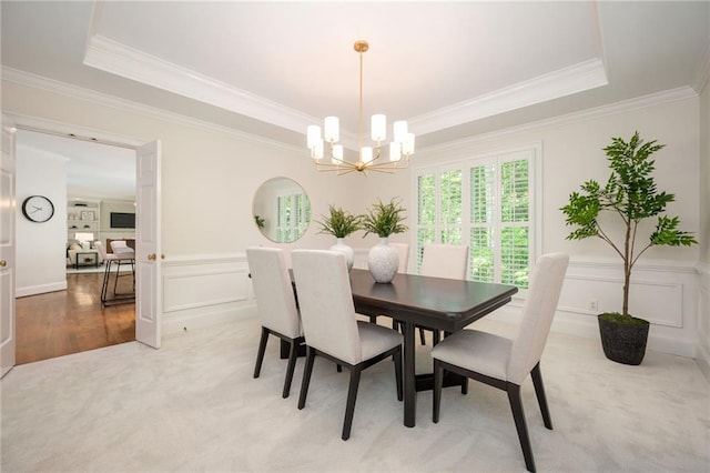 dining space featuring crown molding, a tray ceiling, a notable chandelier, and light carpet