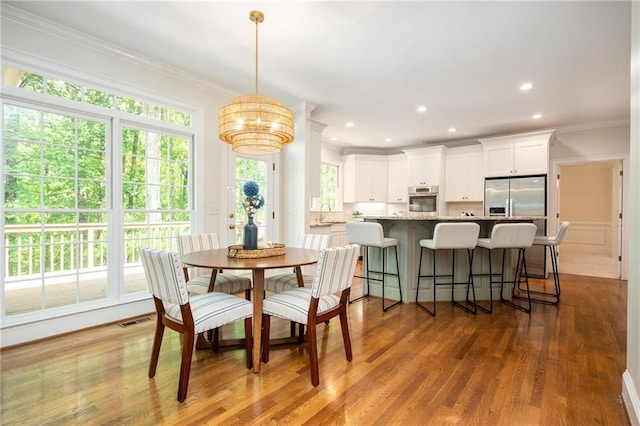 dining room featuring crown molding, a chandelier, wood finished floors, and a wealth of natural light