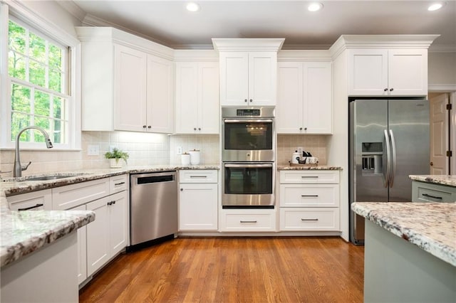 kitchen with a sink, appliances with stainless steel finishes, white cabinetry, and a healthy amount of sunlight