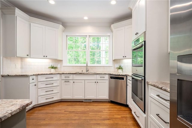 kitchen featuring light wood-style floors, a sink, appliances with stainless steel finishes, and white cabinets