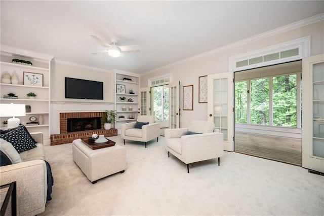 carpeted living area with ceiling fan, french doors, crown molding, a fireplace, and built in shelves
