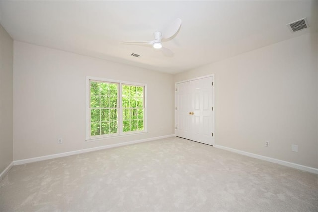 carpeted empty room featuring baseboards, ceiling fan, and visible vents