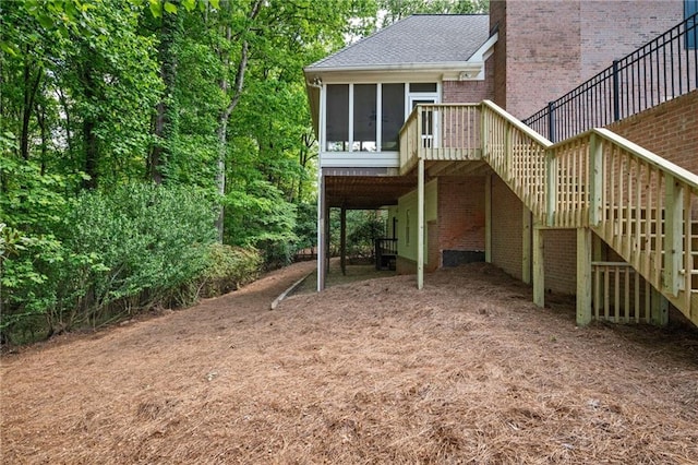 rear view of property with stairway, brick siding, a sunroom, and a deck
