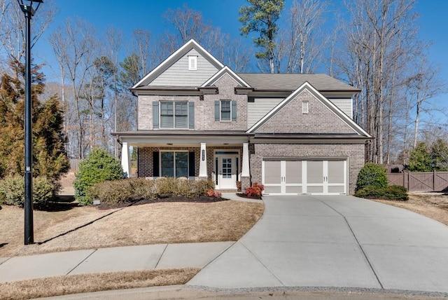 craftsman house featuring brick siding, a porch, fence, a garage, and driveway