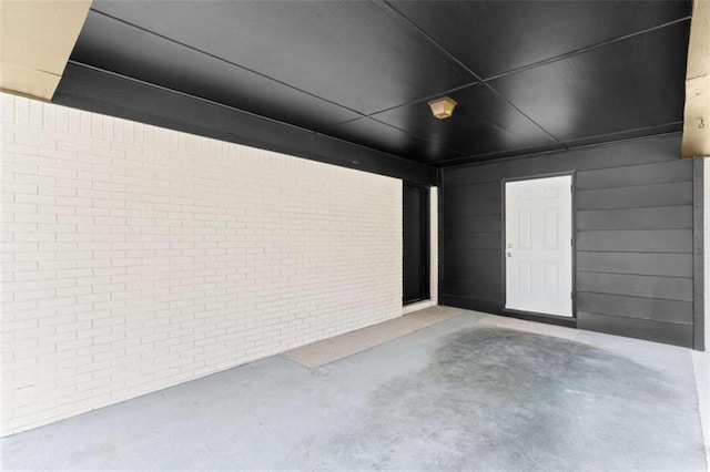 exterior space featuring concrete flooring and brick wall