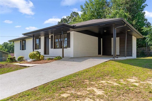 view of front of property with brick siding, concrete driveway, a front yard, and an attached carport