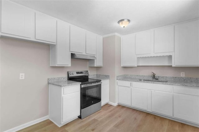 kitchen with electric stove, a sink, under cabinet range hood, and baseboards
