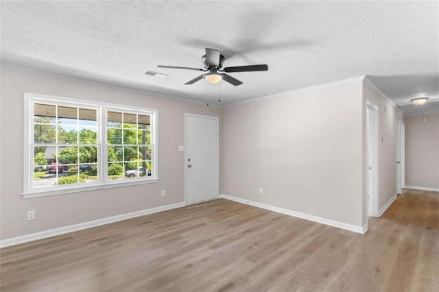empty room with wood finished floors, a textured ceiling, a ceiling fan, baseboards, and ornamental molding