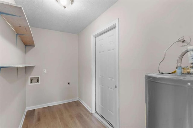 laundry area with water heater, light wood finished floors, electric dryer hookup, a textured ceiling, and baseboards