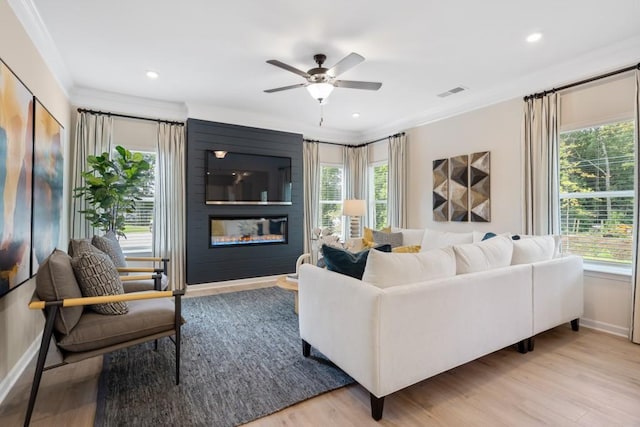 living room with crown molding, a wealth of natural light, visible vents, and a fireplace