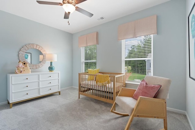 carpeted bedroom with a nursery area, baseboards, visible vents, and a ceiling fan