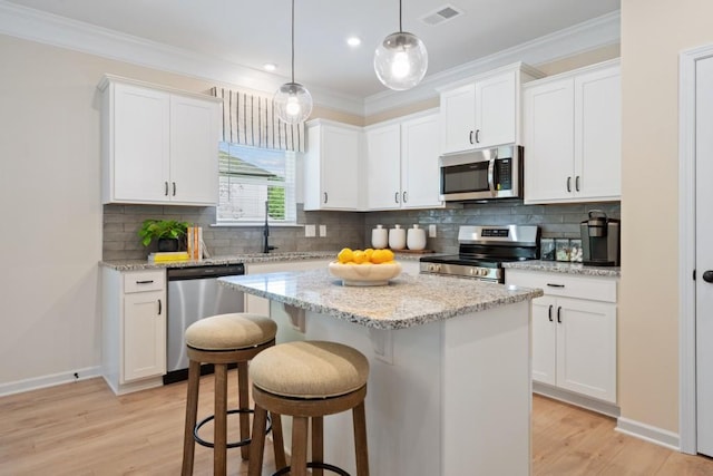 kitchen with stainless steel appliances, a center island, visible vents, and crown molding