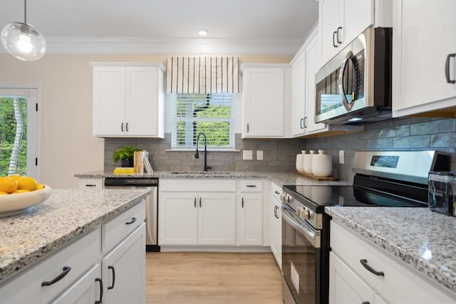 kitchen featuring stainless steel appliances, ornamental molding, a sink, and white cabinetry