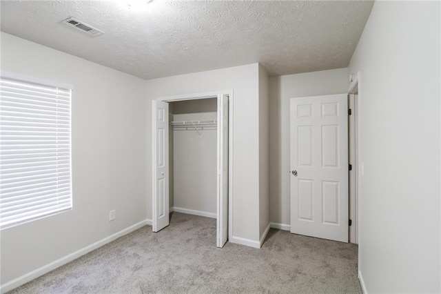 unfurnished bedroom featuring a closet, visible vents, light colored carpet, and baseboards