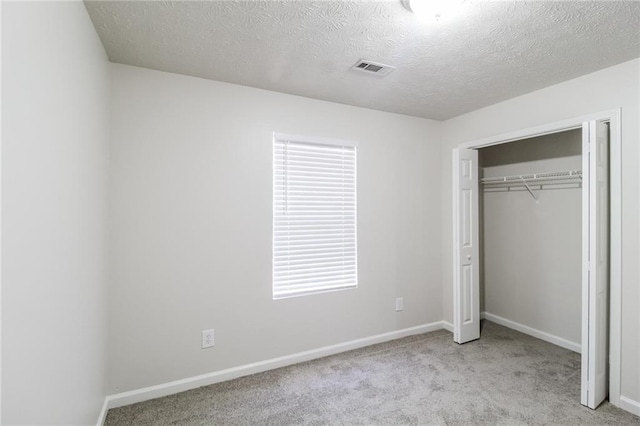 unfurnished bedroom featuring visible vents, baseboards, carpet floors, a closet, and a textured ceiling