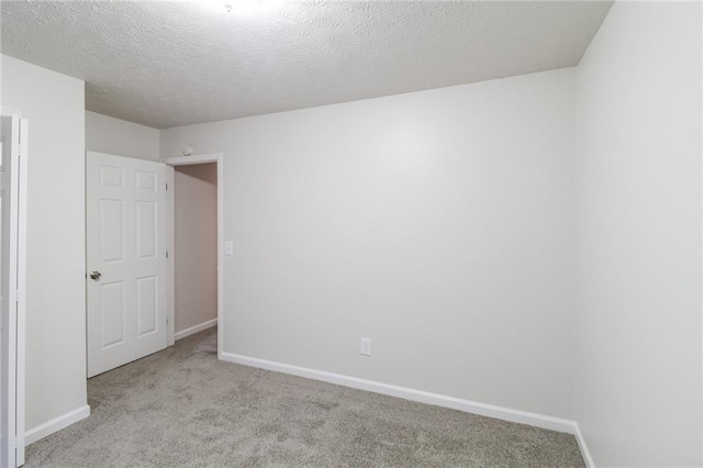 unfurnished bedroom with carpet flooring, a textured ceiling, and baseboards