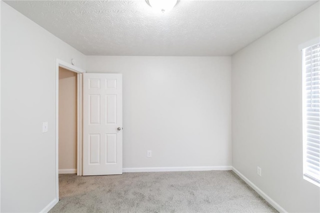 unfurnished room with carpet flooring, baseboards, and a textured ceiling