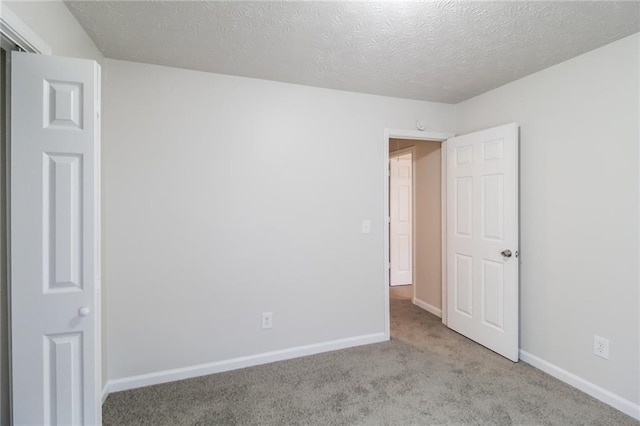 unfurnished bedroom featuring a textured ceiling, baseboards, and carpet floors