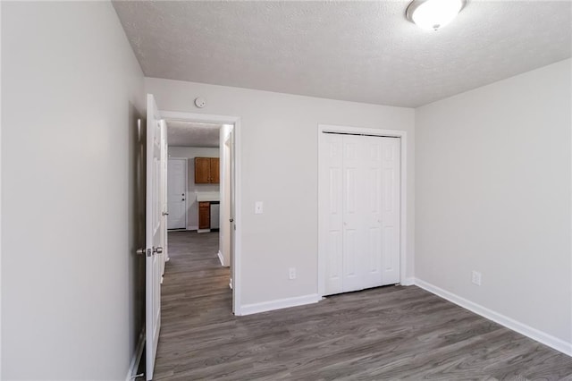 unfurnished bedroom with a closet, baseboards, a textured ceiling, and wood finished floors