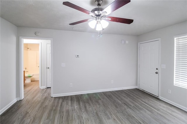 unfurnished room featuring baseboards, a ceiling fan, and wood finished floors